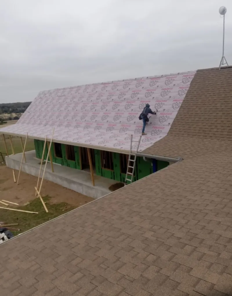 Worker preparing underlayment for a metal roof installation in Morton